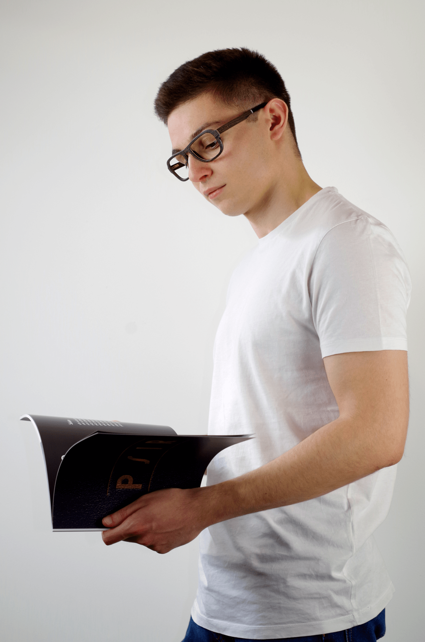 homme tenant un catalogue et portant des lunettes en bois